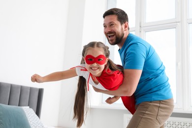Photo of Father and his daughter in superhero costume playing at home