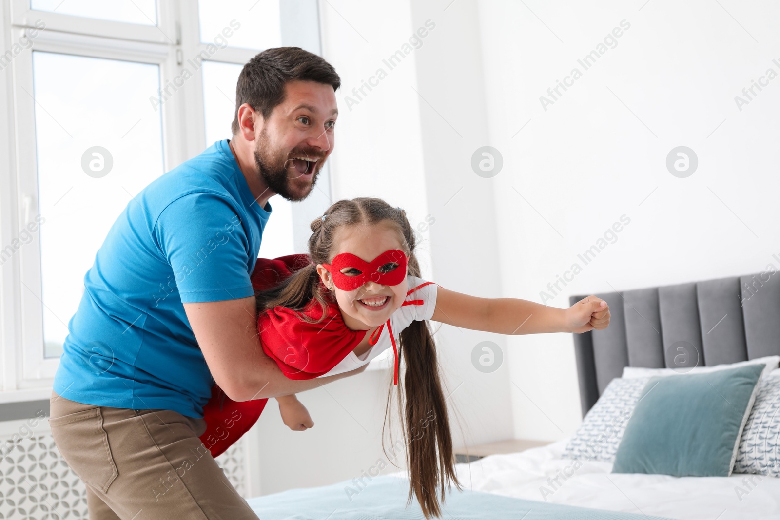 Father and his daughter in superhero costume playing at home Photo of Father and his daughter in superhero costume playing at home