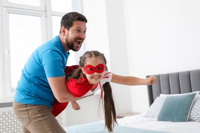 Photo of Father and his daughter in superhero costume playing at home