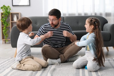 Photo of Children and their father playing on floor at home