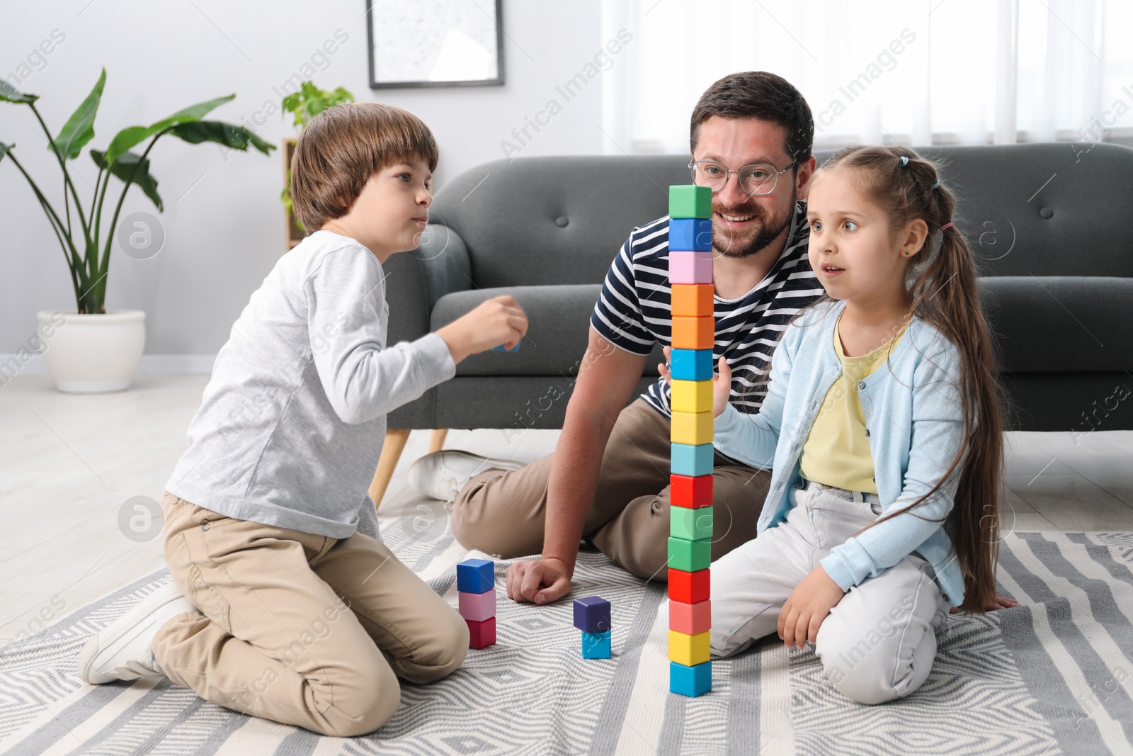 Father and his children playing with colorful cubes on floor at home Photo of Father and his children playing with colorful cubes on floor at home