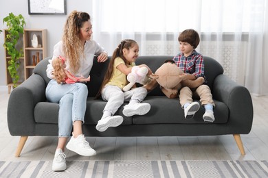 Photo of Children and their mother playing with different toys on sofa at home