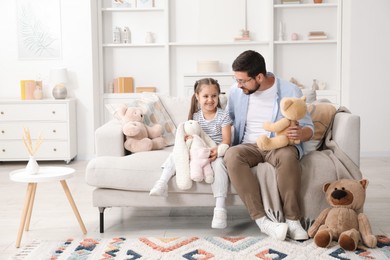 Photo of Father and his daughter playing with stuffed animals on sofa at home