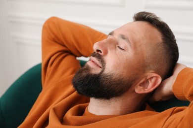 Photo of Harmony. Man relaxing in comfortable armchair at home, closeup