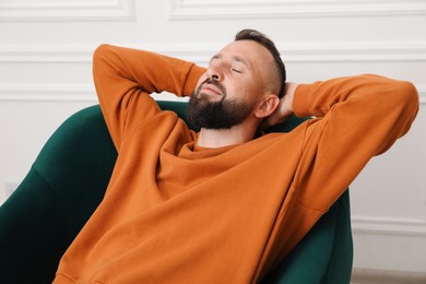 Photo of Harmony. Man relaxing in comfortable armchair at home