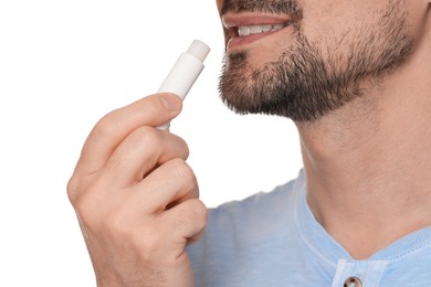 Photo of Smiling man applying lip balm onto his lips on white background, closeup