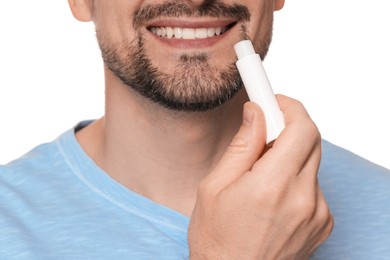 Photo of Smiling man applying lip balm onto his lips on white background, closeup