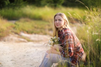 Photo of Beautiful woman with bouquet of wildflowers in meadow. Space for text