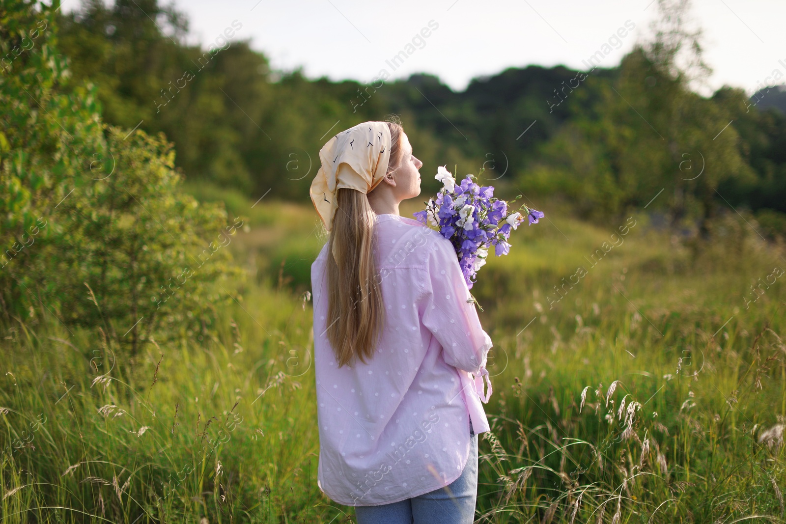 Beautiful woman with bouquet of wildflowers in meadow on sunny day Photo of Beautiful woman with bouquet of wildflowers in meadow on sunny day