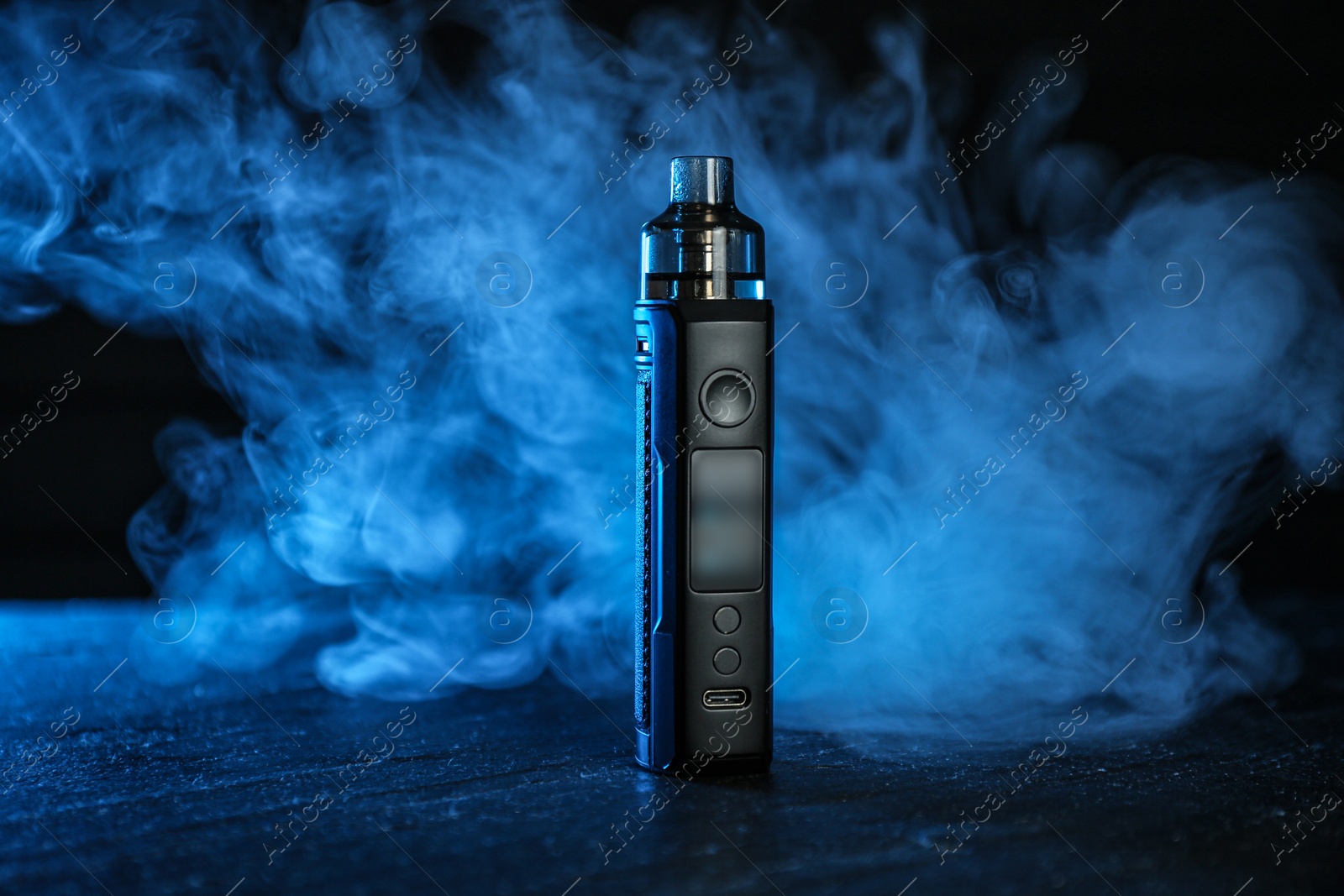 Electronic smoking device on black table in blue light Photo of Electronic smoking device on black table in blue light