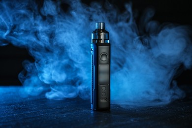 Photo of Electronic smoking device on black table in blue light
