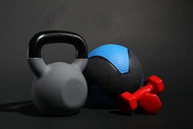 Photo of Medicine ball, dumbbells and kettlebell on black background