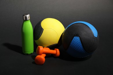 Photo of Medicine balls, dumbbells and water bottle on black background