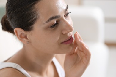 Photo of Young woman with lip balm on her lips at home