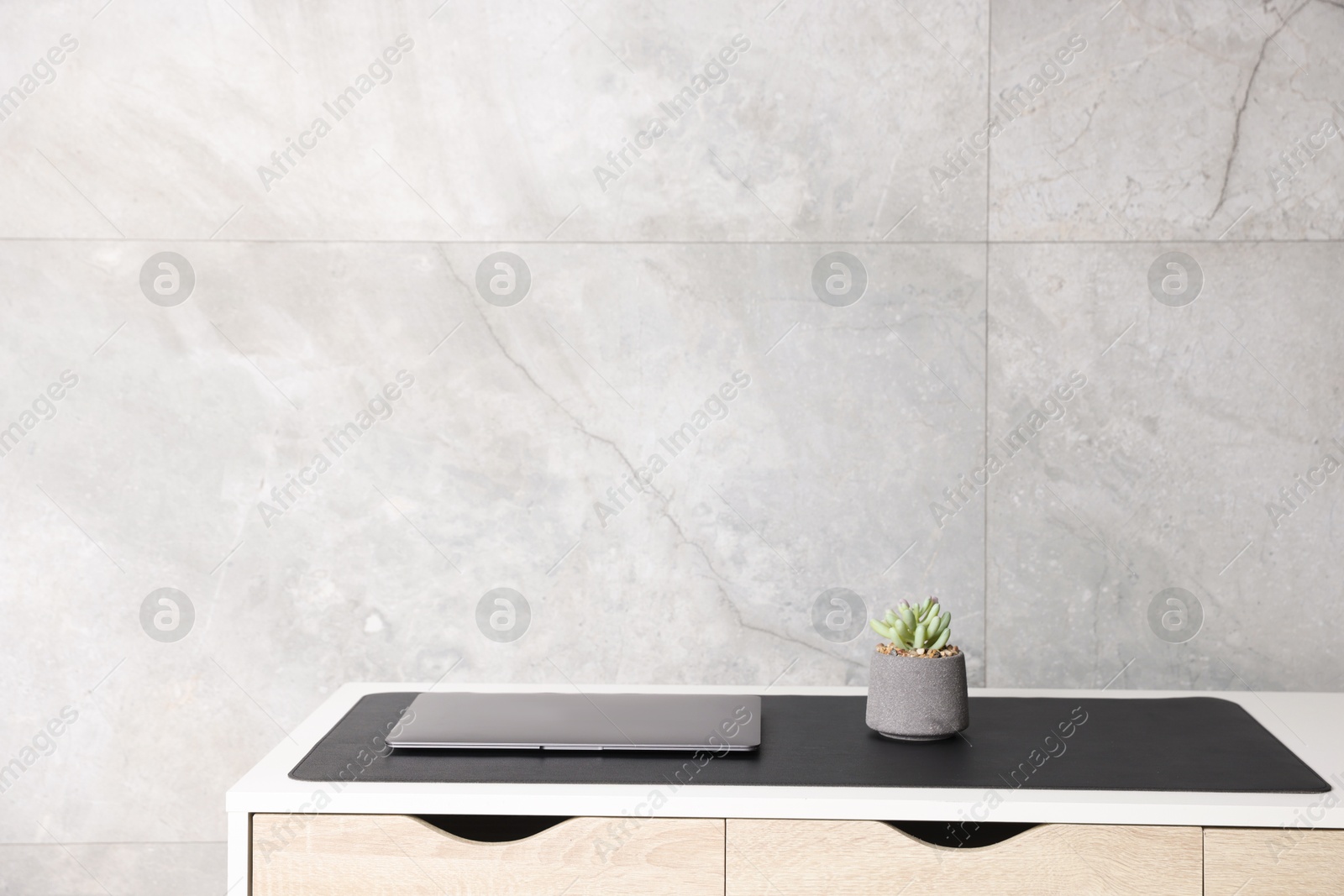 Photo of Stylish workplace with laptop and black mousepad on white table indoors. Space for text