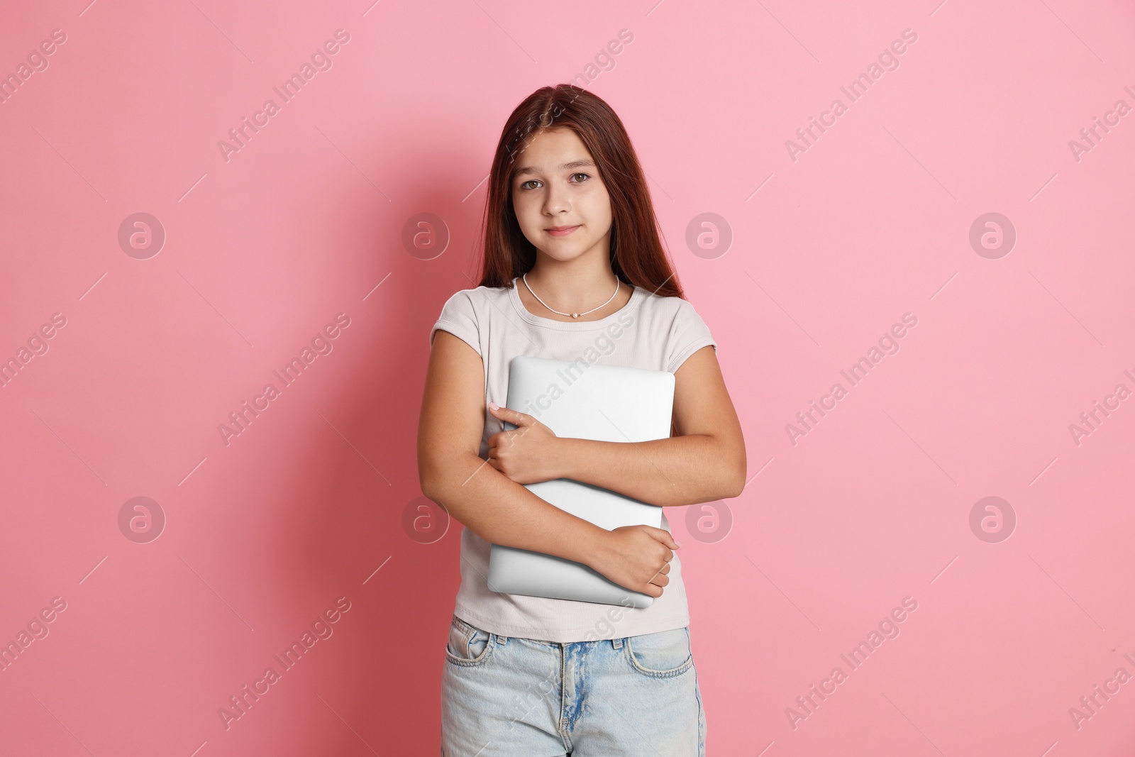 Teenage girl with laptop on pink background Photo of Teenage girl with laptop on pink background