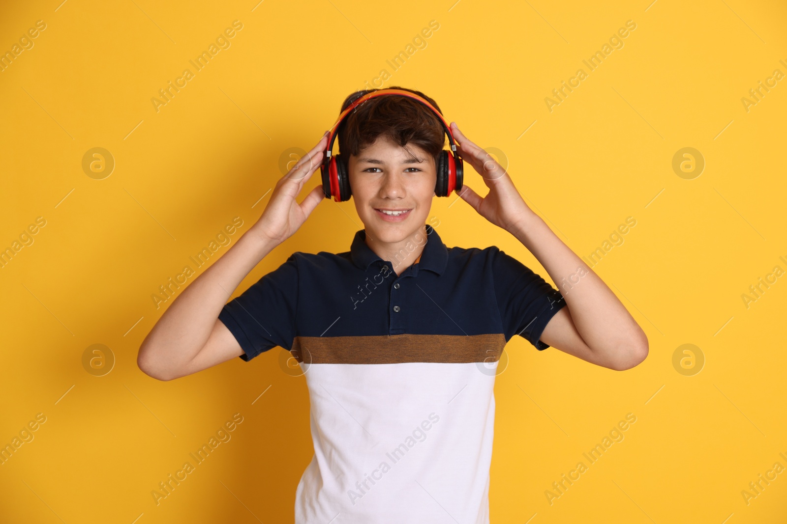 Teenage boy in headphones on orange background Photo of Teenage boy in headphones on orange background