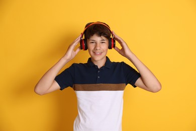 Photo of Teenage boy in headphones on orange background