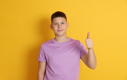 Photo of Teenage boy showing thumbs up on orange background