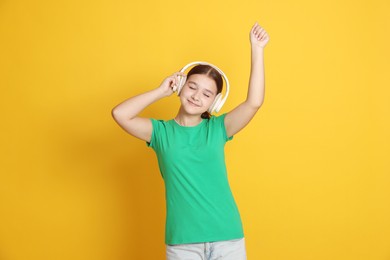 Photo of Teenage girl in headphones on orange background
