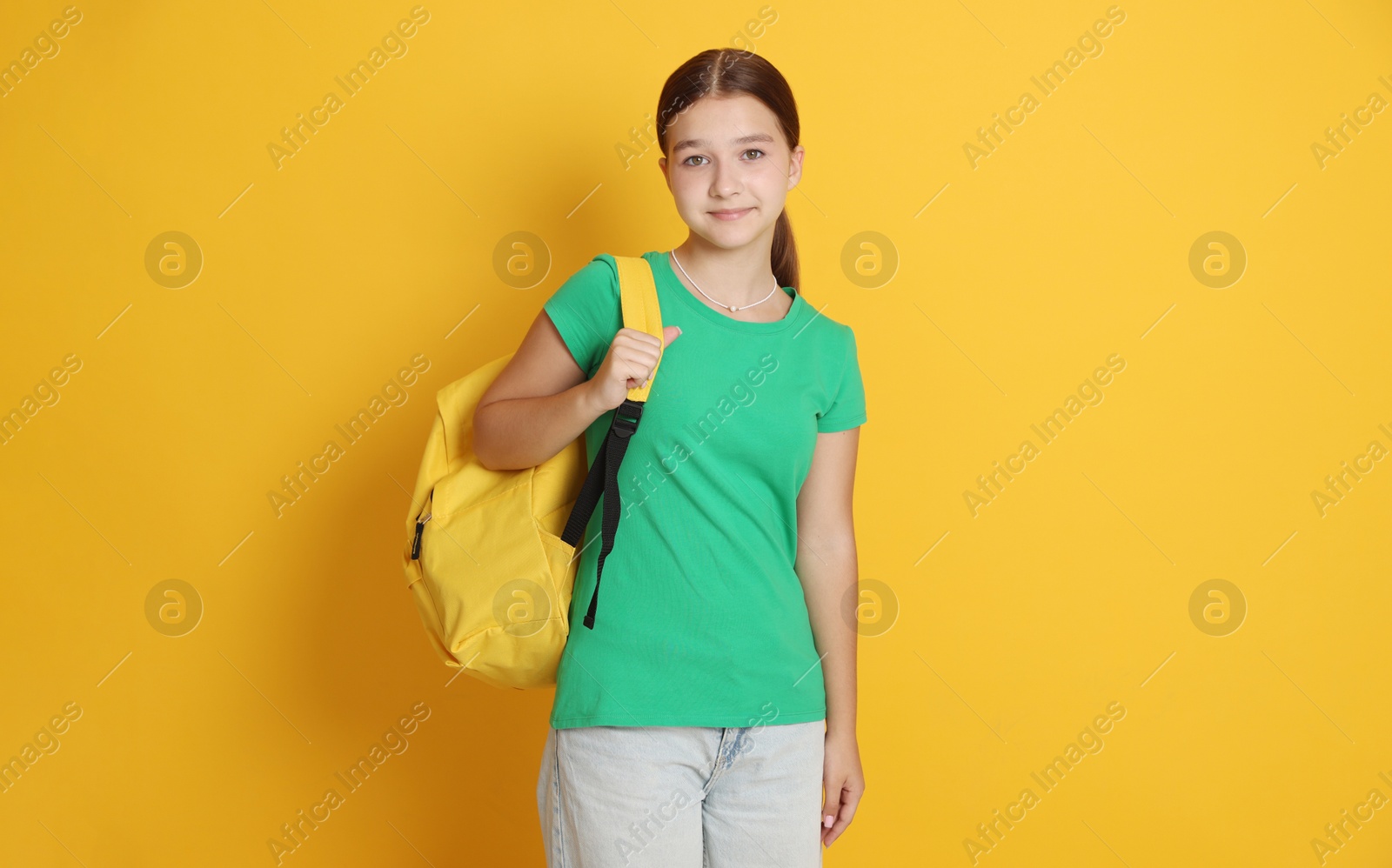 Teenage girl with backpack on orange background Photo of Teenage girl with backpack on orange background