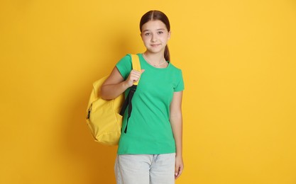 Photo of Teenage girl with backpack on orange background