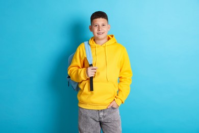 Photo of Teenage boy with backpack on light blue background