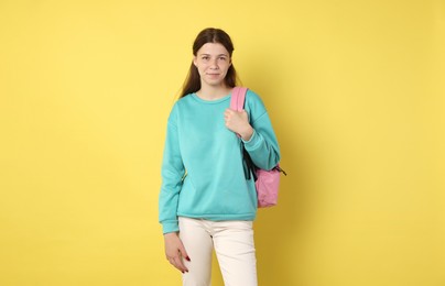 Photo of Teenage girl with backpack on yellow background