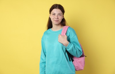 Photo of Teenage girl with backpack on yellow background