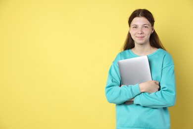 Photo of Teenage girl with laptop on yellow background, space for text