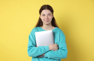 Photo of Teenage girl with laptop on yellow background