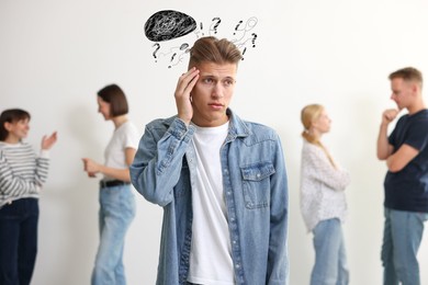 Image of Worried man in room with people. Confused thoughts as doodles coming out of his head. Stress, anxiety, depression