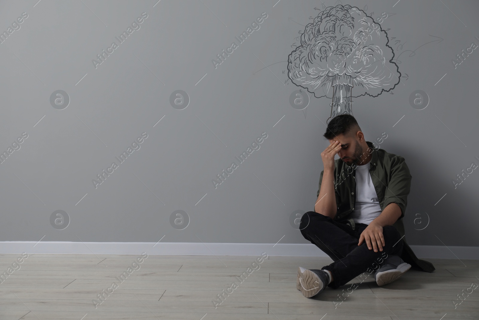 Illustration of Worried man sitting on floor. Confused thoughts depicted by explosion on grey wall behind him. Stress, anxiety, depression