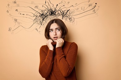 Image of Worried woman on pale brown background. Confused thoughts as doodles coming out of her head. Stress, anxiety, depression