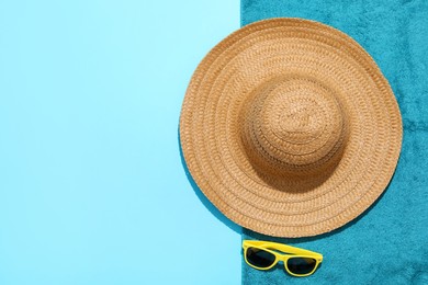 Photo of Straw hat, sunglasses and beach towel on light blue background, top view. Space for text