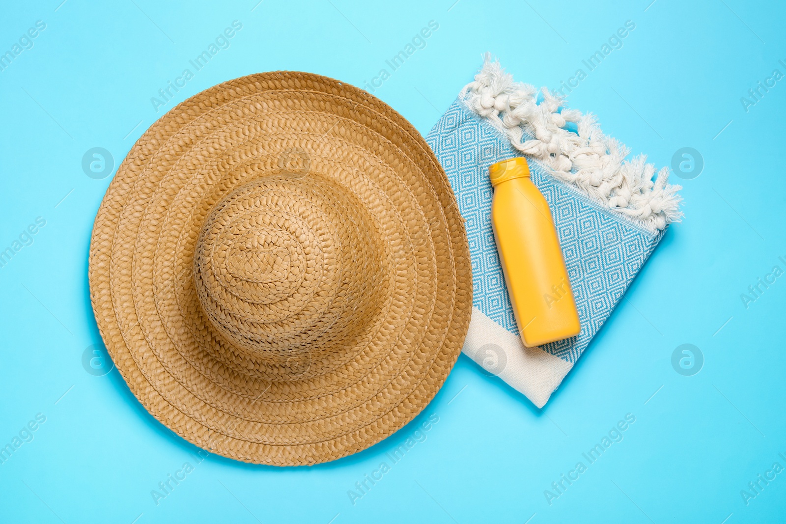 Straw hat, beach towel and sunscreen on light blue background, flat lay Photo of Straw hat, beach towel and sunscreen on light blue background, flat lay