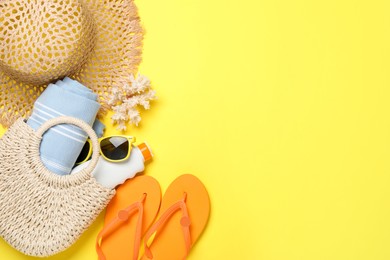 Photo of Flat lay composition with beach towel and other summer accessories on yellow background. Space for text