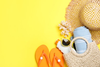 Photo of Flat lay composition with beach towel and other summer accessories on yellow background. Space for text