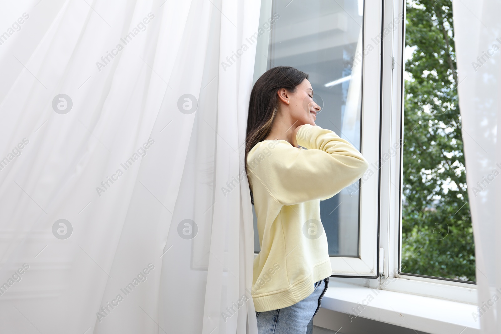 Photo of Harmony. Smiling woman near open window at home