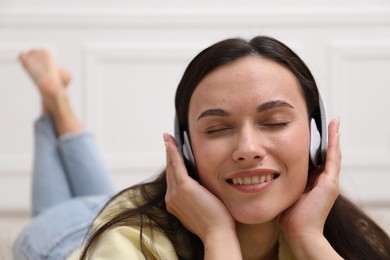 Photo of Harmony. Smiling woman in headphones enjoying music at home, closeup