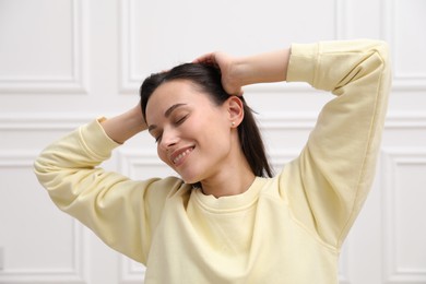 Photo of Harmony. Smiling woman stretching near white wall at home