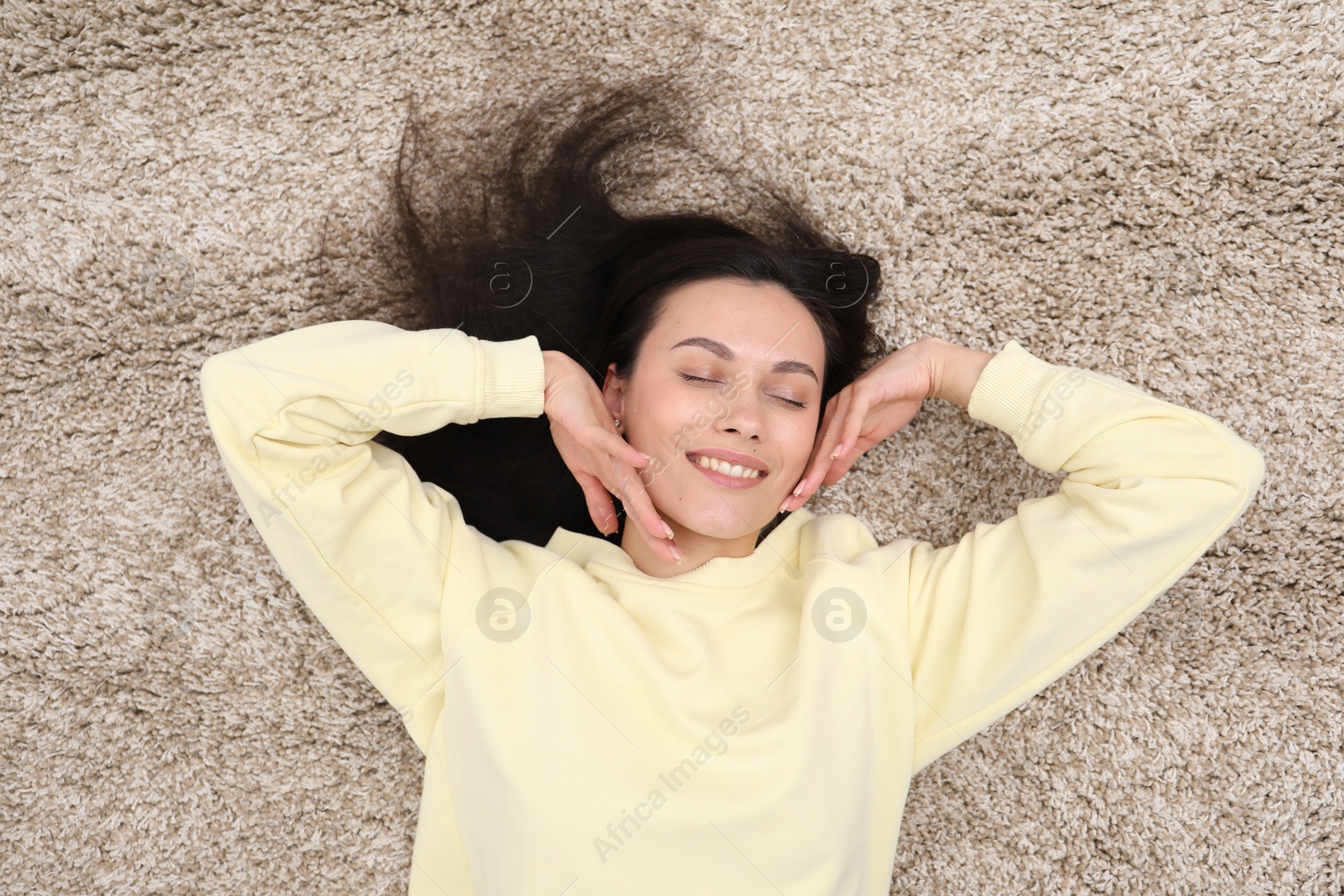 Harmony. Smiling woman relaxing on beige carpet, top view Photo of Harmony. Smiling woman relaxing on beige carpet, top view