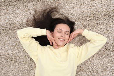 Photo of Harmony. Smiling woman relaxing on beige carpet, top view