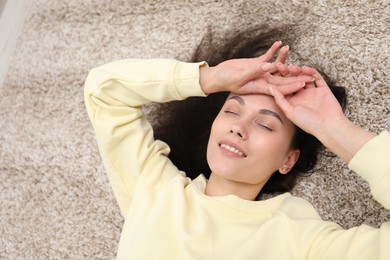 Photo of Harmony. Smiling woman relaxing on beige carpet