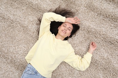 Photo of Harmony. Smiling woman relaxing on beige carpet, top view