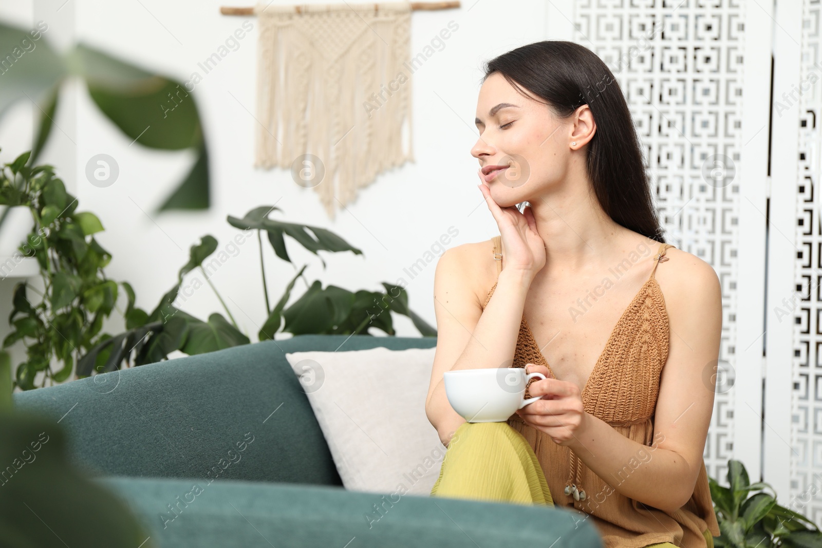 Harmony. Woman with cup of hot drink relaxing on sofa at home Photo of Harmony. Woman with cup of hot drink relaxing on sofa at home