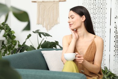 Photo of Harmony. Woman with cup of hot drink relaxing on sofa at home