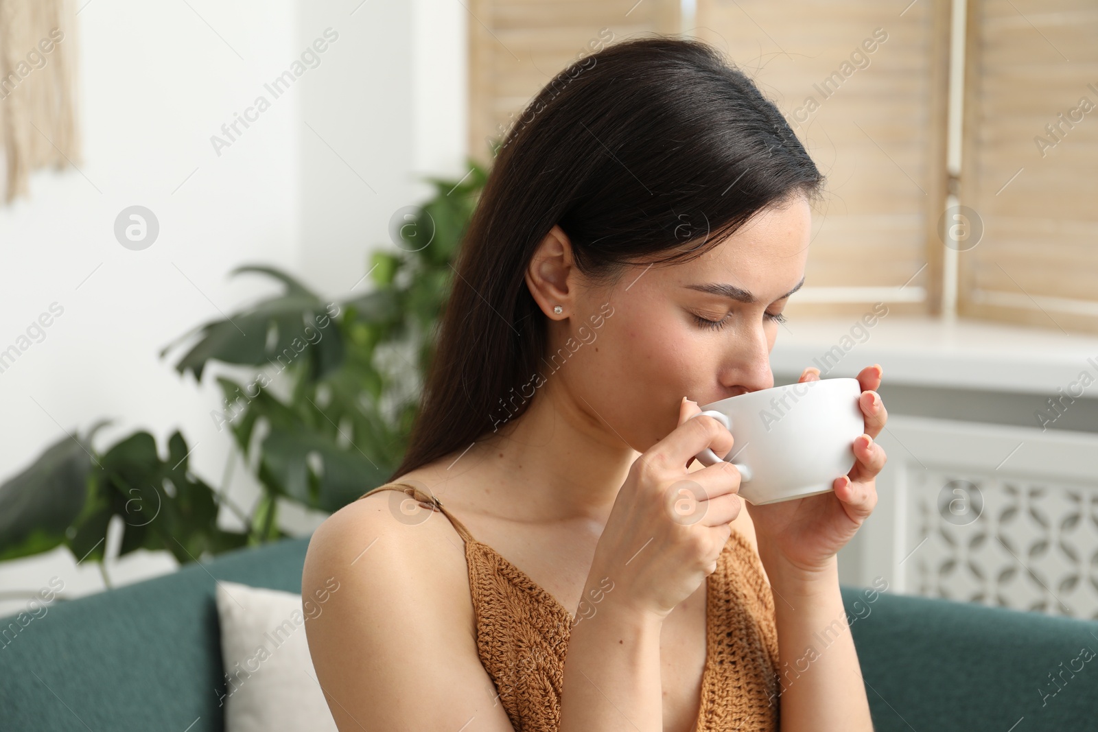 Harmony. Woman with cup of hot drink relaxing on sofa at home Photo of Harmony. Woman with cup of hot drink relaxing on sofa at home