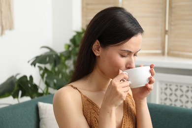 Photo of Harmony. Woman with cup of hot drink relaxing on sofa at home