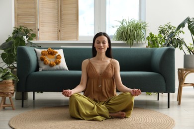 Photo of Harmony. Smiling woman meditating on floor at home